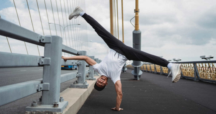 A guy doing a hand stand on bridge