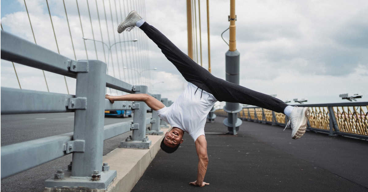 A guy doing a hand stand on bridge