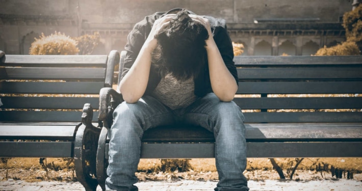 Man stressed on park bench